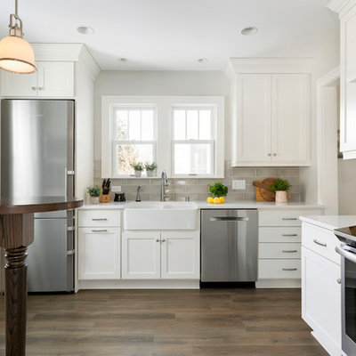 Kitchen - small country l-shaped medium tone wood floor and brown floor kitchen idea in Minneapolis with a farmhouse sink, shaker cabinets, white cabinets, gray backsplash, subway tile backsplash, stainless steel appliances, a peninsula and white countertops