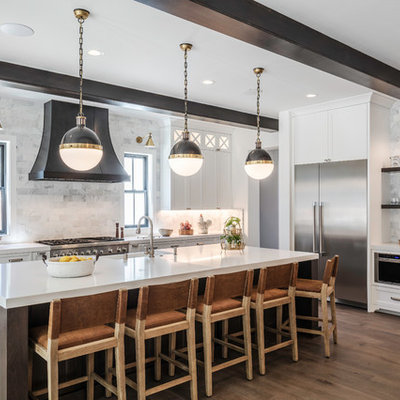 Example of a large transitional l-shaped medium tone wood floor and brown floor open concept kitchen design in San Francisco with a farmhouse sink, shaker cabinets, white cabinets, quartz countertops, gray backsplash, marble backsplash, stainless steel appliances, an island and white countertops