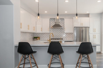 Inspiration for a mid-sized transitional l-shaped dark wood floor and brown floor open concept kitchen remodel in Orange County with a farmhouse sink, beaded inset cabinets, white cabinets, marble countertops, white backsplash, subway tile backsplash, stainless steel appliances and a peninsula