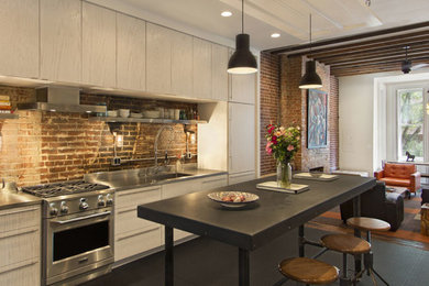 Example of a mid-sized minimalist galley open concept kitchen design in Chicago with flat-panel cabinets, light wood cabinets, stainless steel countertops, an island, a drop-in sink and stainless steel appliances