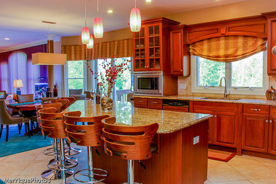 Trendy ceramic tile kitchen photo in New York with an undermount sink, raised-panel cabinets, medium tone wood cabinets, granite countertops, beige backsplash, stainless steel appliances and an island