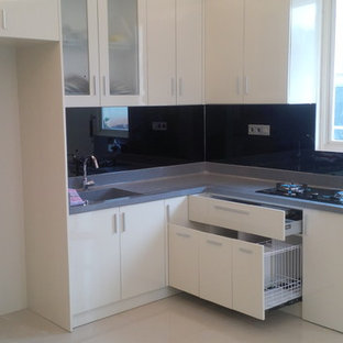 Small asian l-shaped kitchen pantry in Other with a drop-in sink, flat-panel cabinets, white cabinets, solid surface benchtops, black splashback, glass sheet splashback, black appliances, marble floors and no island.