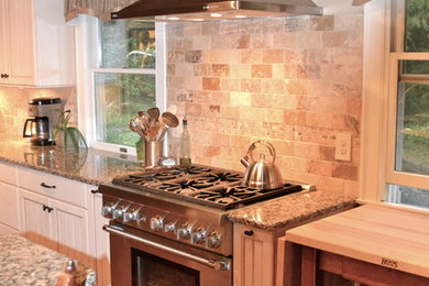 Example of a country u-shaped eat-in kitchen design in New York with an undermount sink, recessed-panel cabinets, beige cabinets, granite countertops, beige backsplash, stone tile backsplash and stainless steel appliances