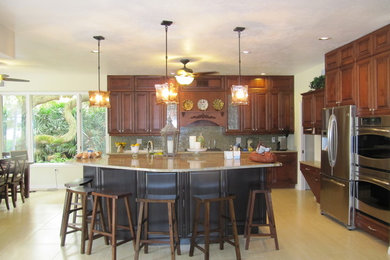 Example of a large classic single-wall porcelain tile eat-in kitchen design in Tampa with an undermount sink, raised-panel cabinets, medium tone wood cabinets, quartz countertops, green backsplash, glass sheet backsplash and stainless steel appliances