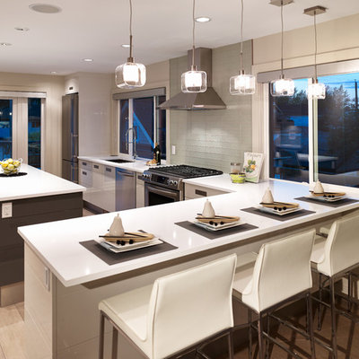 Trendy l-shaped kitchen photo in Vancouver with flat-panel cabinets, stainless steel appliances, white cabinets, glass tile backsplash and white backsplash