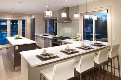 Moderne Küche in L-Form mit flächenbündigen Schrankfronten, Küchengeräten aus Edelstahl, weißen Schränken, Rückwand aus Glasfliesen und Küchenrückwand in Weiß in Vancouver