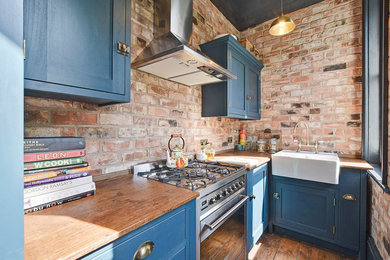 Diseño de cocinas en L actual pequeña con armarios estilo shaker, puertas de armario azules, encimera de madera, electrodomésticos de acero inoxidable, suelo de madera oscura y suelo marrón