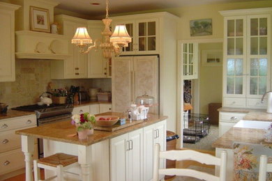 This is an example of a medium sized traditional l-shaped kitchen/diner in Burlington with a belfast sink, raised-panel cabinets, white cabinets, stainless steel appliances and an island.