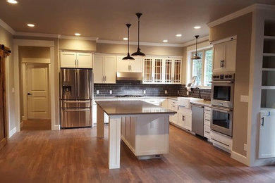 Kitchen - mid-sized transitional l-shaped medium tone wood floor kitchen idea in Other with a farmhouse sink, recessed-panel cabinets, white cabinets, quartzite countertops, gray backsplash, subway tile backsplash, stainless steel appliances and an island