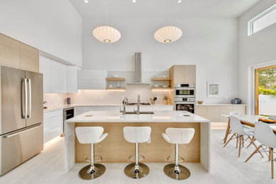Example of a mid-sized minimalist l-shaped light wood floor and white floor open concept kitchen design in Tampa with a single-bowl sink, flat-panel cabinets, light wood cabinets, quartz countertops, white backsplash, ceramic backsplash, stainless steel appliances, an island and white countertops