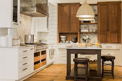 Example of a mid-sized l-shaped light wood floor and brown floor enclosed kitchen design in Boston with recessed-panel cabinets, white cabinets, marble countertops, white backsplash, marble backsplash, stainless steel appliances and an island