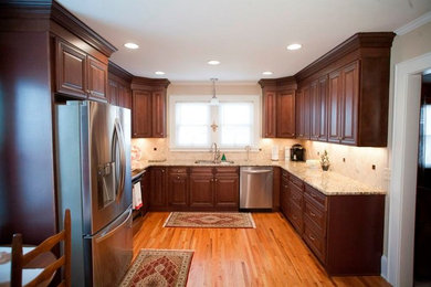 Transitional u-shaped eat-in kitchen photo in Charlotte with an undermount sink, raised-panel cabinets, dark wood cabinets, granite countertops, beige backsplash, subway tile backsplash and stainless steel appliances