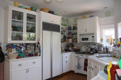 Arts and crafts l-shaped eat-in kitchen photo in Los Angeles with a drop-in sink, beaded inset cabinets, white cabinets, tile countertops, white backsplash, ceramic backsplash and white appliances