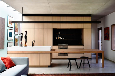 Foto de cocina lineal actual con armarios con paneles lisos, puertas de armario de madera clara, encimera de madera, suelo de cemento y una isla