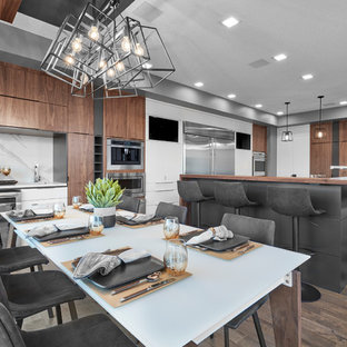 Photo of a mid-sized contemporary kitchen in Edmonton with an undermount sink, louvered cabinets, white cabinets, wood benchtops, grey splashback, porcelain splashback, stainless steel appliances, medium hardwood floors, brown floor and brown benchtop.