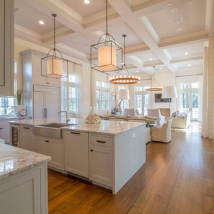 Immagine di una cucina ad ambiente unico costiera con lavello stile country, ante in stile shaker, ante bianche, parquet scuro e isola