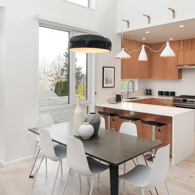 Example of a trendy u-shaped light wood floor and beige floor eat-in kitchen design in Portland with an undermount sink, flat-panel cabinets, medium tone wood cabinets, white backsplash, stainless steel appliances, a peninsula and white countertops