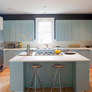 This is an example of a tropical u-shaped kitchen in Miami with a double-bowl sink, flat-panel cabinets, blue cabinets and stainless steel appliances.
