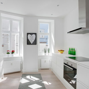 Foto di una cucina parallela scandinava di medie dimensioni con lavello sottopiano, ante lisce, ante bianche, elettrodomestici in acciaio inossidabile, parquet chiaro, nessuna isola e top in laminato