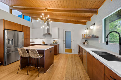 Example of a mid-sized 1950s u-shaped light wood floor, brown floor and exposed beam enclosed kitchen design in Birmingham with an undermount sink, flat-panel cabinets, medium tone wood cabinets, quartz countertops, blue backsplash, ceramic backsplash, stainless steel appliances, an island and white countertops