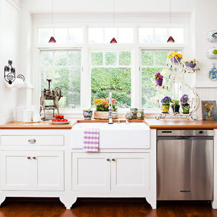 Mid-sized shabby-chic style l-shaped kitchen in Los Angeles with a farmhouse sink, shaker cabinets, white cabinets, wood benchtops, white splashback, stainless steel appliances, medium hardwood floors and with island.