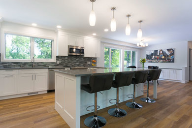 Inspiration for a mid-sized modern l-shaped vinyl floor and brown floor eat-in kitchen remodel in Other with an undermount sink, shaker cabinets, white cabinets, quartz countertops, multicolored backsplash, glass tile backsplash, stainless steel appliances and a peninsula