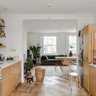 Inspiration for an eclectic galley kitchen in London with flat-panel cabinets, medium wood cabinets, white splashback, light hardwood flooring, no island, beige floors and white worktops.