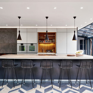 Medium sized contemporary galley open plan kitchen in Devon with a single-bowl sink, flat-panel cabinets, grey cabinets, concrete worktops, brown splashback, wood splashback, stainless steel appliances, light hardwood flooring, an island, multi-coloured floors and grey worktops.