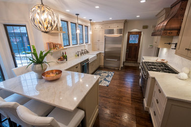 Example of a mid-sized ornate medium tone wood floor and brown floor eat-in kitchen design in Indianapolis with a farmhouse sink, beaded inset cabinets, beige cabinets, quartzite countertops, beige backsplash, porcelain backsplash, stainless steel appliances and a peninsula