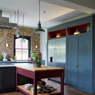 Design ideas for an expansive eclectic kitchen in London with pink cabinets, wood benchtops, shaker cabinets, stainless steel appliances and multiple islands.
