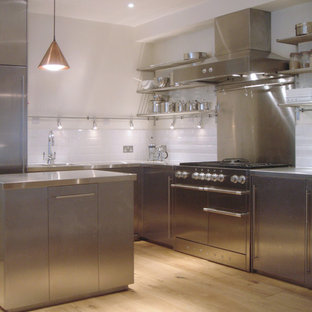 Inspiration for a mid-sized contemporary l-shaped open plan kitchen in London with an integrated sink, flat-panel cabinets, stainless steel cabinets, stainless steel benchtops, white splashback, cement tile splashback, stainless steel appliances, light hardwood floors, with island and beige floor.