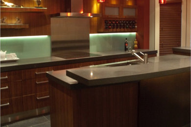 Bild på ett mellanstort funkis kök, med en undermonterad diskho, släta luckor, skåp i mörkt trä, bänkskiva i terrazo, grönt stänkskydd, glaspanel som stänkskydd, rostfria vitvaror, klinkergolv i porslin och en köksö