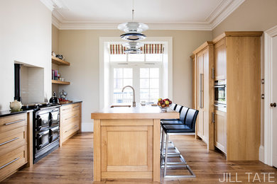 Ejemplo de cocina comedor clásica con armarios estilo shaker, puertas de armario de madera oscura, encimera de granito, suelo de madera en tonos medios y una isla