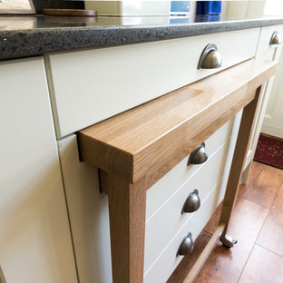 Mid-sized victorian u-shaped separate kitchen in Other with a farmhouse sink, shaker cabinets, white cabinets, recycled glass benchtops, white splashback, glass sheet splashback, white appliances, medium hardwood floors and no island.