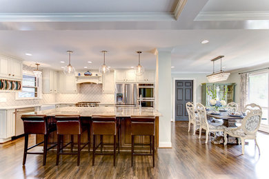 Example of a mid-sized transitional u-shaped dark wood floor eat-in kitchen design in Birmingham with a farmhouse sink, raised-panel cabinets, distressed cabinets, granite countertops, gray backsplash, ceramic backsplash, stainless steel appliances and an island