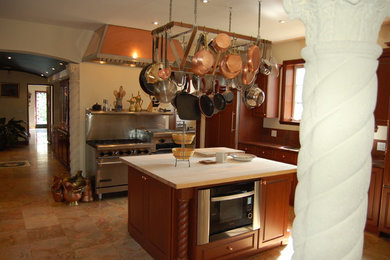 Exempel på ett avskilt, stort medelhavsstil brun brunt u-kök, med en undermonterad diskho, luckor med upphöjd panel, skåp i mörkt trä, bänkskiva i akrylsten, stänkskydd med metallisk yta, stänkskydd i metallkakel, rostfria vitvaror, skiffergolv, en köksö och beiget golv