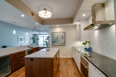 Large trendy u-shaped medium tone wood floor and brown floor open concept kitchen photo in Tampa with an undermount sink, flat-panel cabinets, white cabinets, quartzite countertops, white backsplash, mosaic tile backsplash, stainless steel appliances and an island
