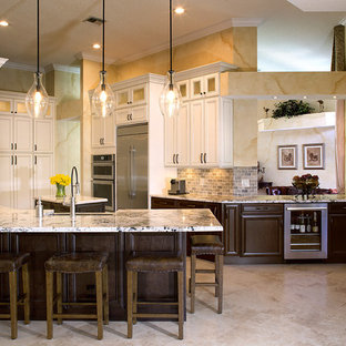 Idee per una grande cucina ad U classica chiusa con ante bianche, top in quarzite, paraspruzzi beige, paraspruzzi con piastrelle in pietra, elettrodomestici in acciaio inossidabile, lavello stile country, ante con riquadro incassato, penisola e pavimento beige