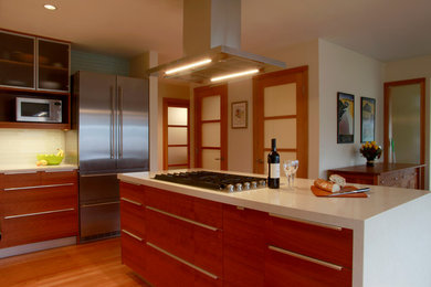 Eat-in kitchen - mid-sized contemporary l-shaped medium tone wood floor eat-in kitchen idea in Seattle with a double-bowl sink, glass-front cabinets, medium tone wood cabinets, quartz countertops, blue backsplash, glass tile backsplash, stainless steel appliances and an island