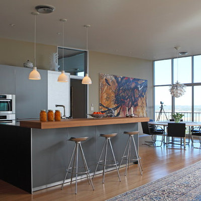 Open concept kitchen - contemporary open concept kitchen idea in Austin with wood countertops, flat-panel cabinets, gray cabinets and stainless steel appliances