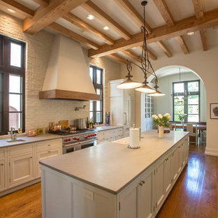 Large mediterranean kitchen remodeling - Large tuscan galley medium tone wood floor kitchen photo in Austin with white cabinets, paneled appliances, an island, recessed-panel cabinets and white backsplash