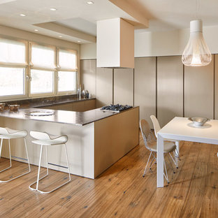 Ispirazione per una cucina minimal con ante lisce, ante beige, lavello sottopiano, pavimento in legno massello medio, penisola, pavimento marrone, top in marmo, paraspruzzi nero, paraspruzzi in marmo, elettrodomestici in acciaio inossidabile e top nero