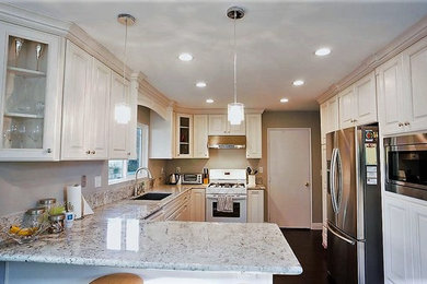 Example of a large transitional u-shaped dark wood floor and brown floor enclosed kitchen design in San Diego with an undermount sink, glass-front cabinets, white cabinets, quartzite countertops, window backsplash, stainless steel appliances and a peninsula