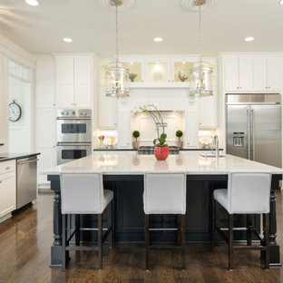 Transitional kitchen remodeling - Example of a transitional u-shaped dark wood floor and brown floor kitchen design in Kansas City with an undermount sink, shaker cabinets, white cabinets, stainless steel appliances, an island and white countertops