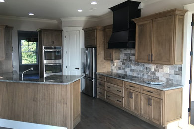 Enclosed kitchen - mid-sized transitional u-shaped dark wood floor enclosed kitchen idea in Atlanta with an undermount sink, shaker cabinets, distressed cabinets, granite countertops, gray backsplash, stone tile backsplash, stainless steel appliances and a peninsula