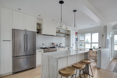 Minimalist medium tone wood floor and beige floor eat-in kitchen photo in Vancouver with an undermount sink, shaker cabinets, white cabinets, quartz countertops, white backsplash, ceramic backsplash, stainless steel appliances, an island and white countertops