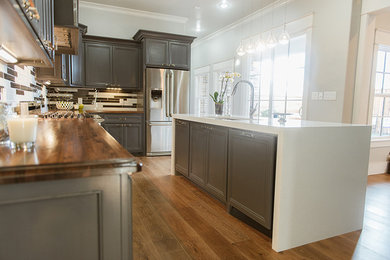 Inspiration for a mid-sized eclectic l-shaped light wood floor open concept kitchen remodel in Dallas with an undermount sink, shaker cabinets, gray cabinets, wood countertops, multicolored backsplash, matchstick tile backsplash, stainless steel appliances and an island