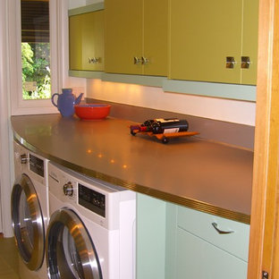 This is an example of a mid-sized midcentury galley separate kitchen in Portland with a drop-in sink, flat-panel cabinets, green cabinets, laminate benchtops, metallic splashback, stainless steel appliances, vinyl floors and no island.