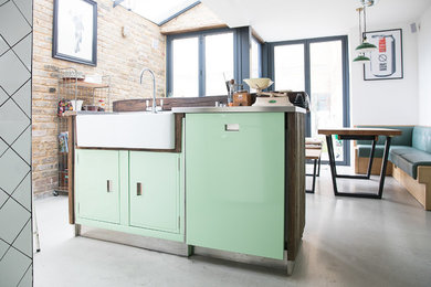 Inspiration for a large industrial kitchen in London with green cabinets, stainless steel worktops, concrete flooring, an island, grey floors and grey worktops.