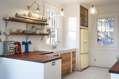 Example of a mid-sized eclectic l-shaped ceramic tile open concept kitchen design in Austin with a double-bowl sink, flat-panel cabinets, light wood cabinets, wood countertops, white backsplash and colored appliances